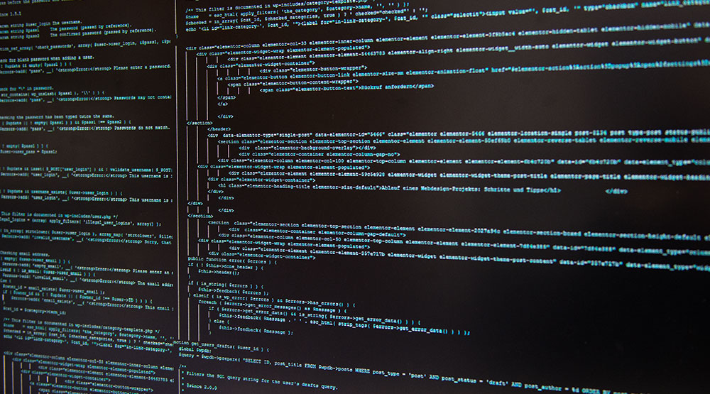 Nahaufnahme eines Computerbildschirms mit zwei Spalten von Programmiercode in türkisfarbener Schrift auf schwarzem Hintergrund